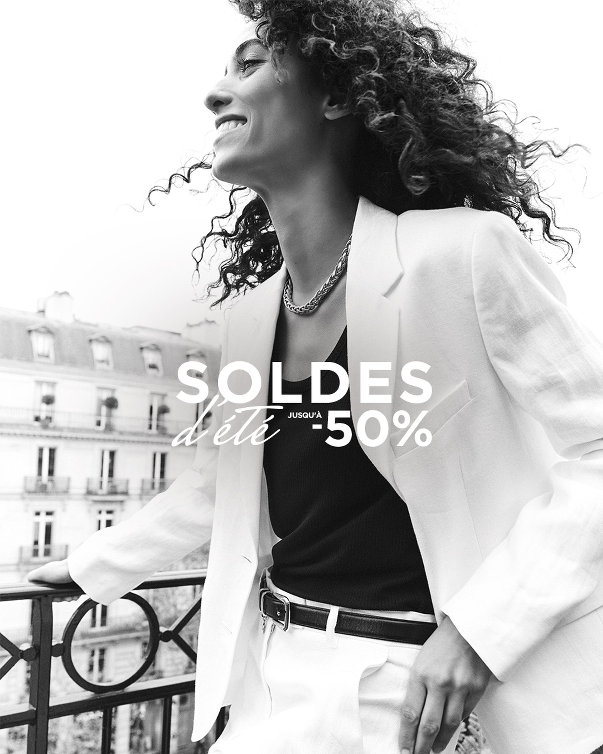 Woman in a white suit smiling on a balcony with "Soldes d'été -50%" text. Parisian building facade in the background.