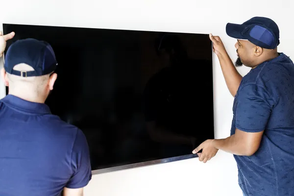 Two Guys Placing Tv On Mount