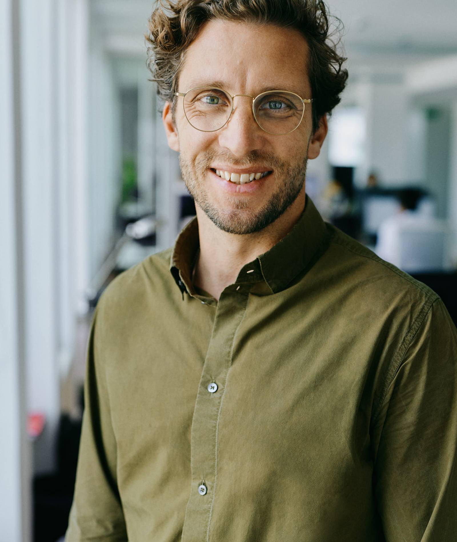 KAMANO-Gründer Philipp lacht vor einem Büro-Raum.