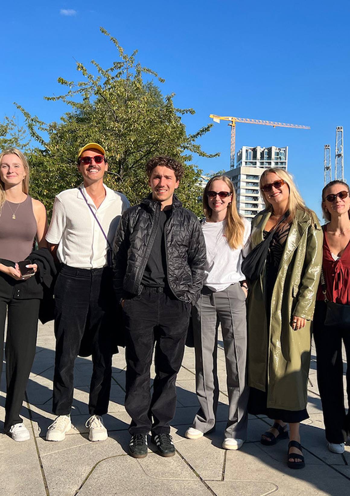 Sechs KAMANO-Teammitglieder lächeln vor einem Hafen in Hamburg.