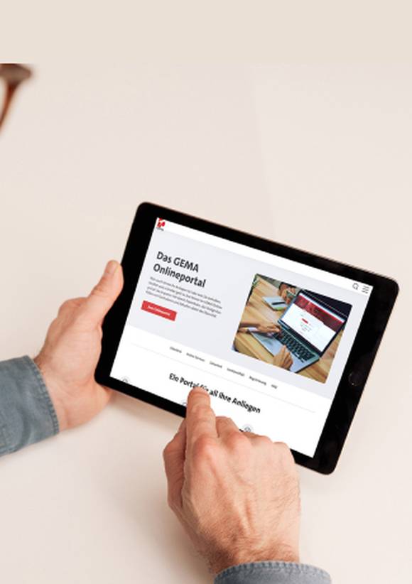 Mann mit Bart in grauem Hemd hält ein Tablet mit der GEMA-Website.