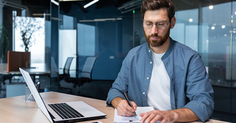 Accountant working in office with laptop and notepad