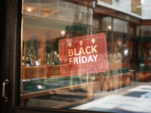 Red "BLACK FRIDAY" sign hangs on a shop window, blurred jewelry display cases visible inside.