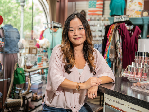 shop and retail small business owner smiling in her premises with diverse products