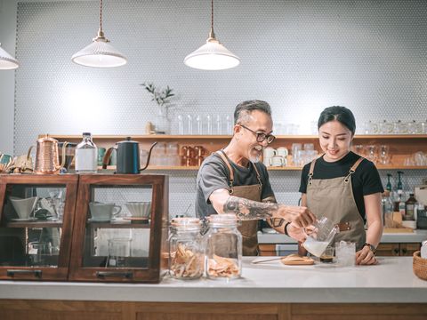 cafe shop owner training employee on coffee making