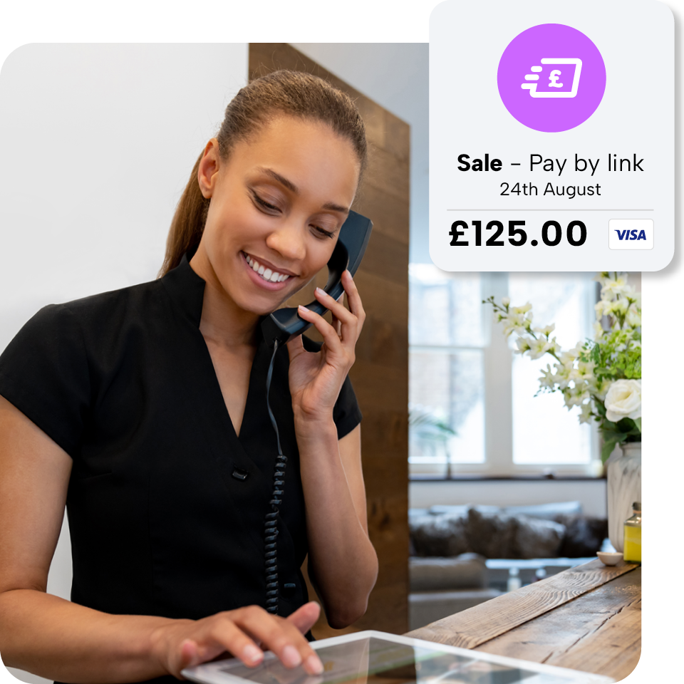 Smiling woman in black uniform talks on phone, uses tablet. Sale notification: "Pay by link, 24th August, £125.00, Visa" displayed.