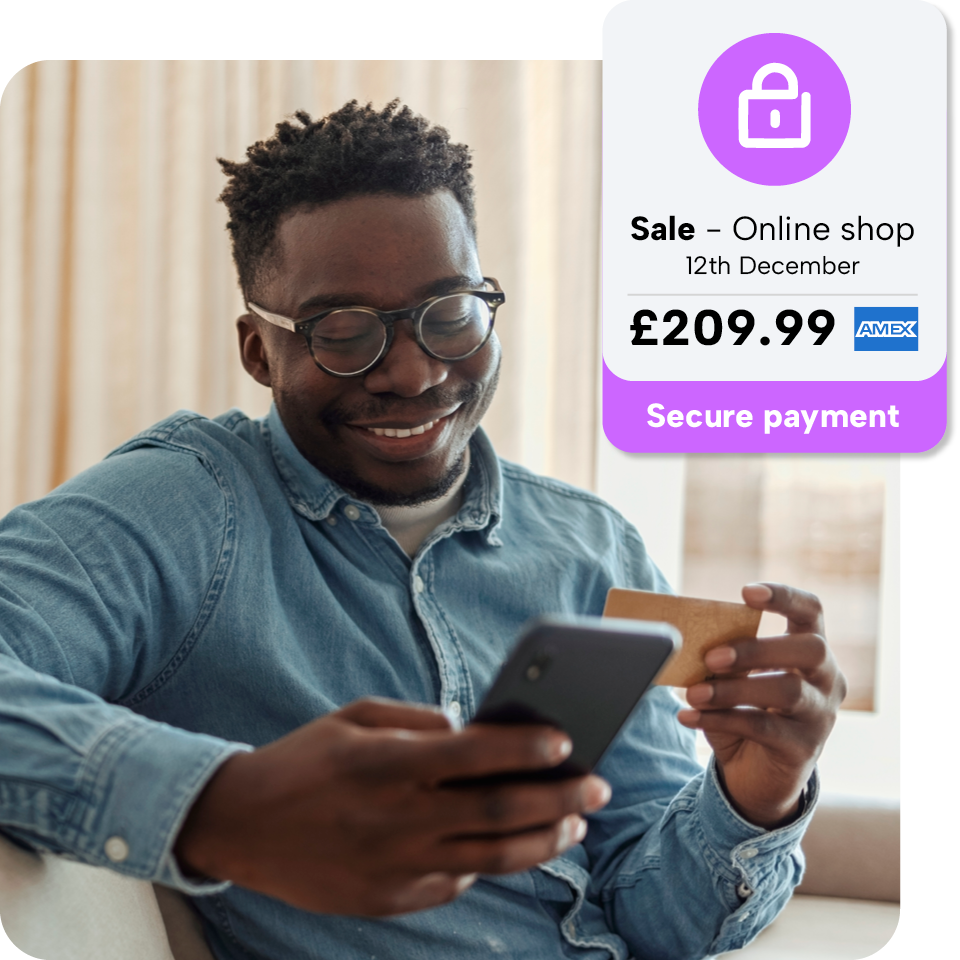 Man smiling while holding a smartphone and credit card, with a secure payment notification for an online shop sale of £209.99.