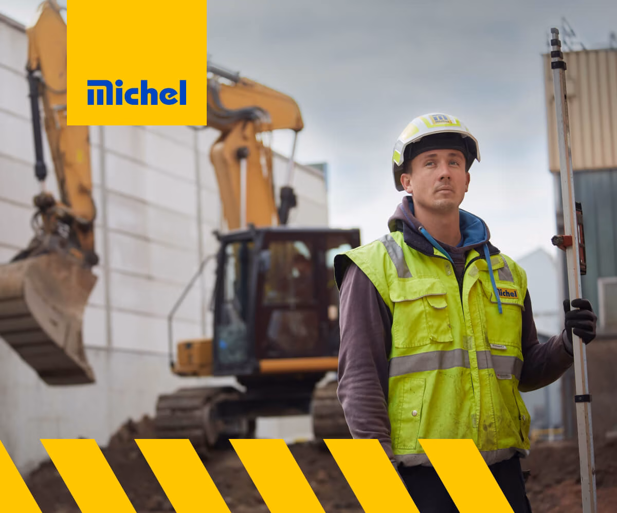 Mann auf der Baustelle mit Bagger im Hintergrund und Michel Bau Logo