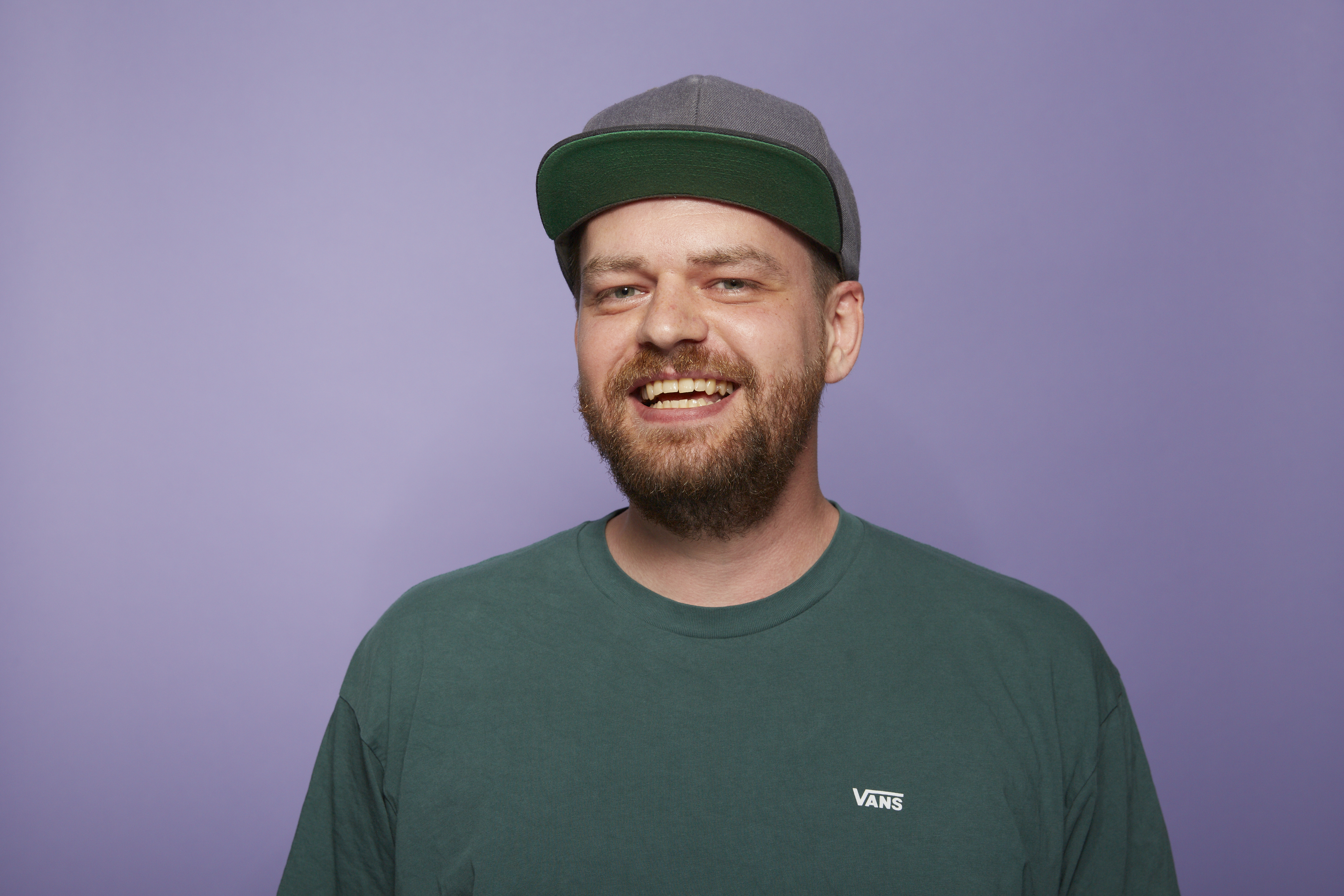 David Isaak, Head of Headless Team bei ONEDOT, mit grünem Shirt vor lila Hintergrund