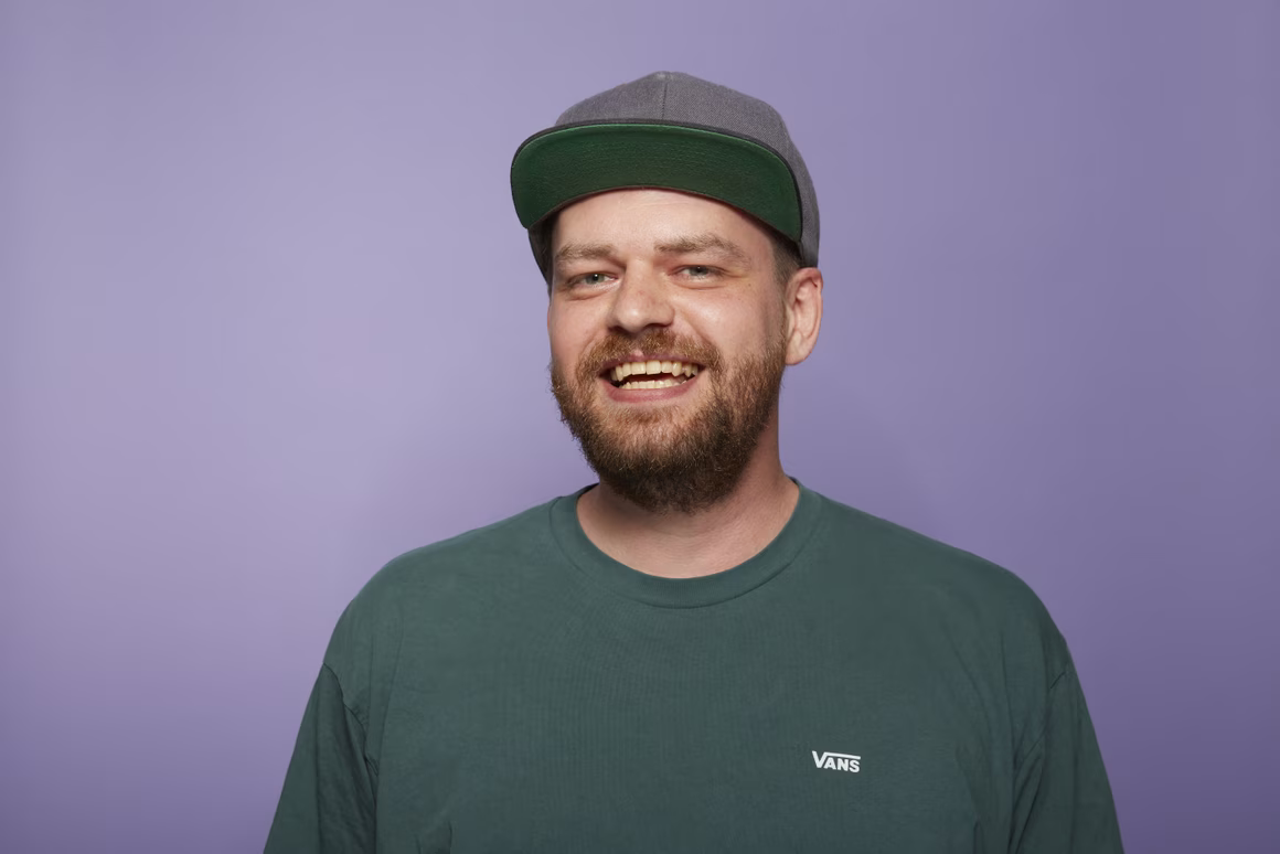 David Isaak, Head of Headless Team bei ONEDOT, mit grünem Shirt vor lila Hintergrund