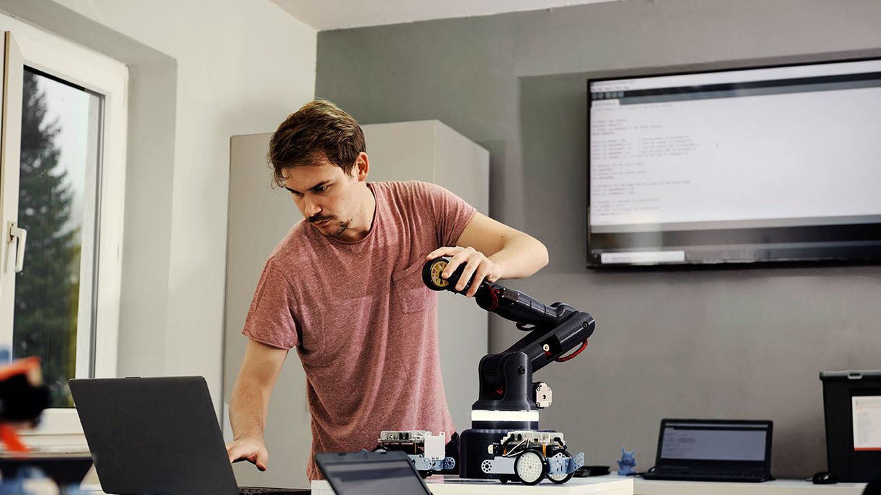 Mann programmiert einen Roboterarm