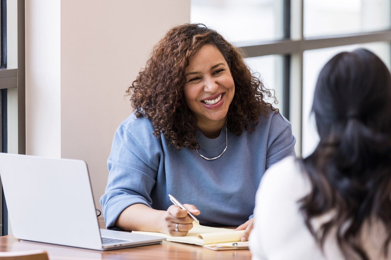 Zwei Frauen sitzen in einem Meeting in einem Büro