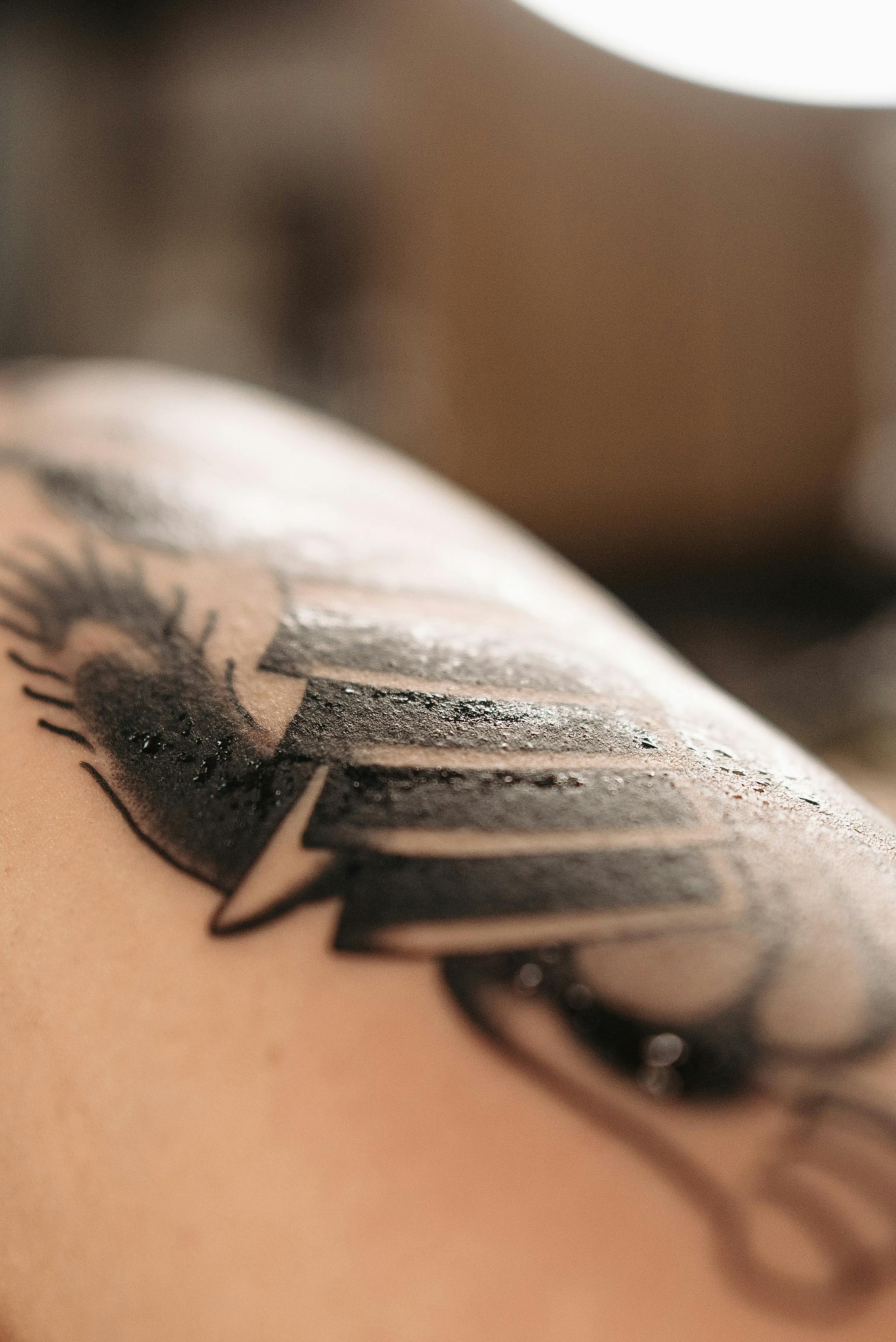 Close-up of a fresh tattoo featuring a stylized eye with prominent eyelashes and bold lines, slightly glistening on the skin.