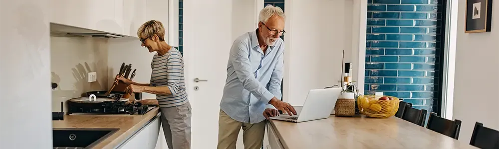 couple in their kitchen looking at smaller houses online as they think about downsizing