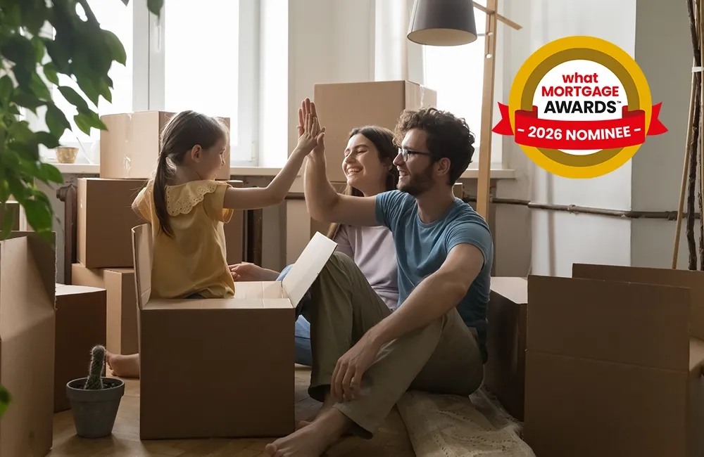 Family celebrates in a new home, surrounded by moving boxes. A "What Mortgage Awards 2026 Nominee" badge is displayed in the corner.