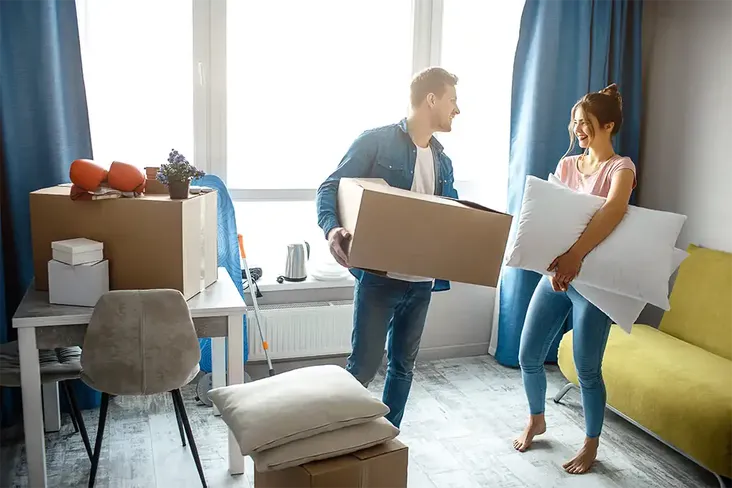 a couple packing up their spare bedroom having just exchanged contracts for their new house