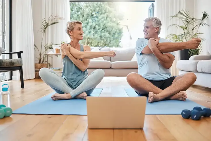 married homeowners doing yoga in their tidy living room after clearing it to prepare it for house viewers