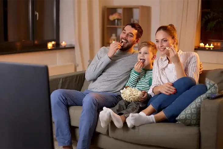a family having a movie night trying to save money and improve their credit score before the buy a new house
