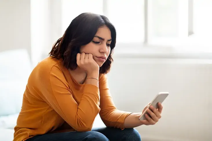 young woman looking at her phone disappointed as her house purchase has fallen through due to being gazumped