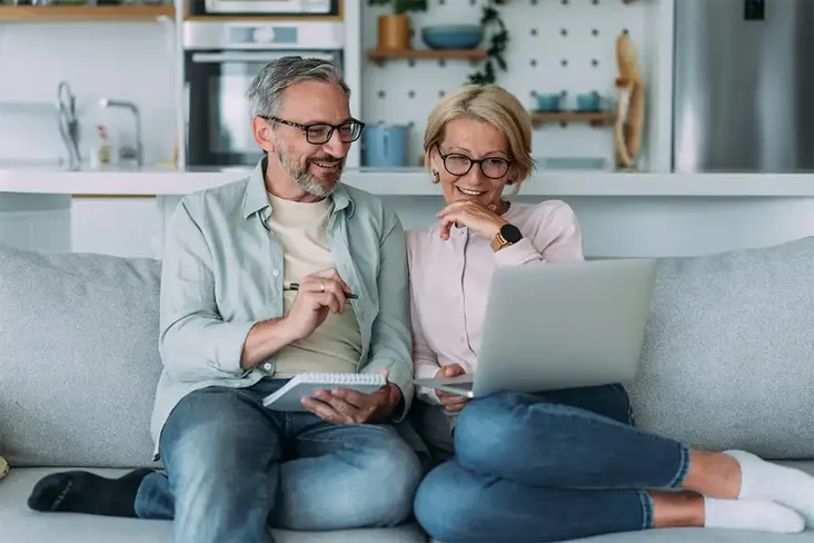 mature couple sitting on the sofa looking at houses to buy as a second home