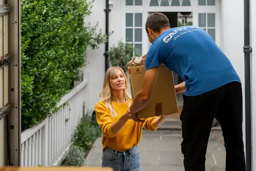 women giving box of belongings to home removals driver