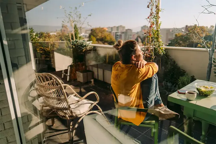young woman sitting on her leasehold flat balcony in sunshine