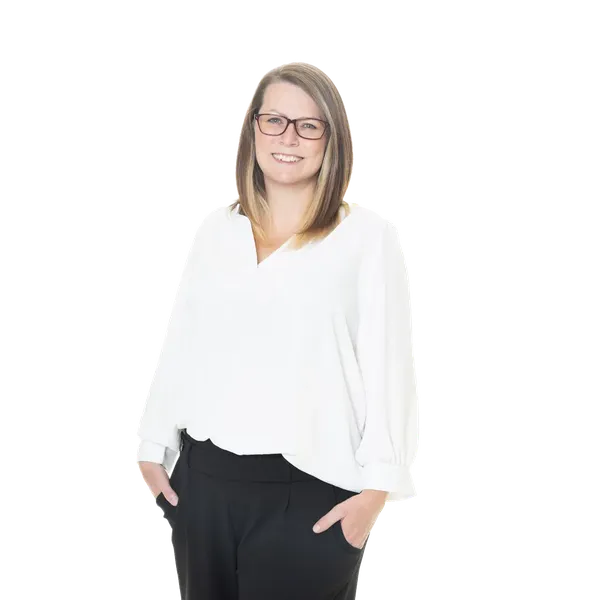 Smiling woman with glasses in a white blouse and black pants, hands in pockets