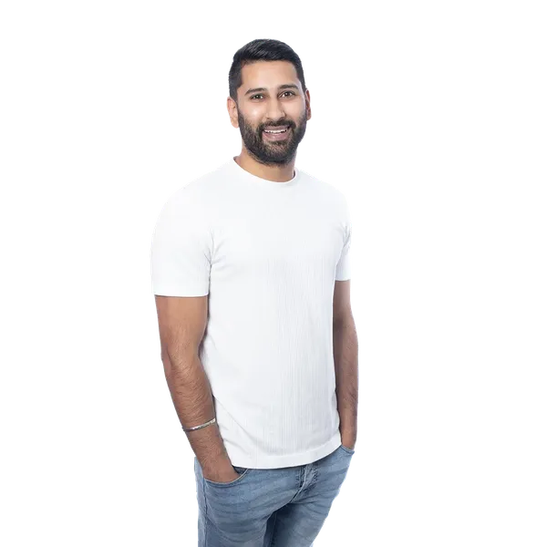 A smiling man in a white t-shirt and jeans stands against a white background with hands in pockets.