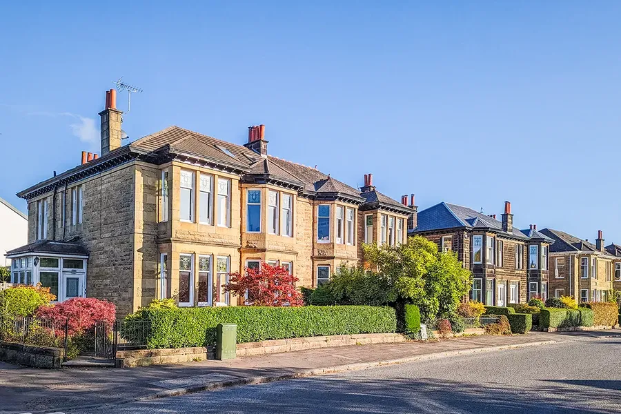 wide street of large bay fronted, yellow stone houses in scotland. The sun is shining and the houses are looking very beautiful