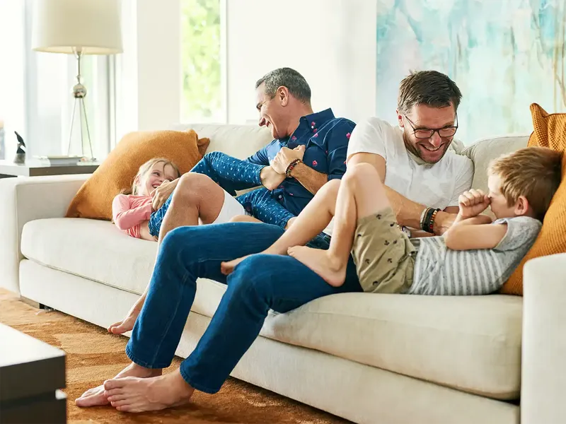 Two dads playing with their children enjoying their home having just moved in