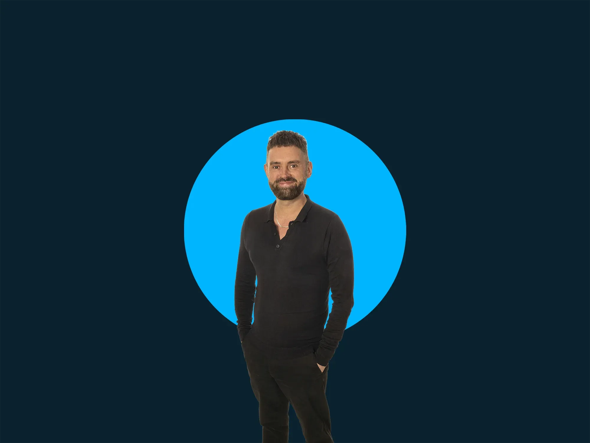 Man in black outfit stands against a dark background with a bright blue circle.