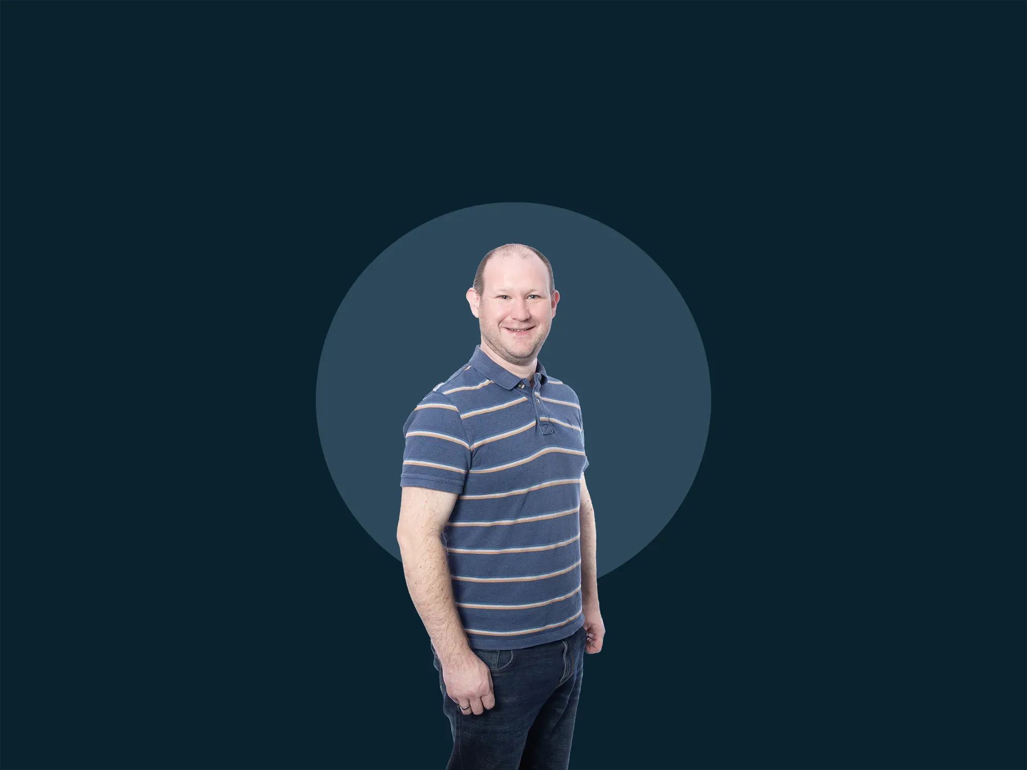 Smiling man in a striped polo shirt stands against a dark background with a circular design.