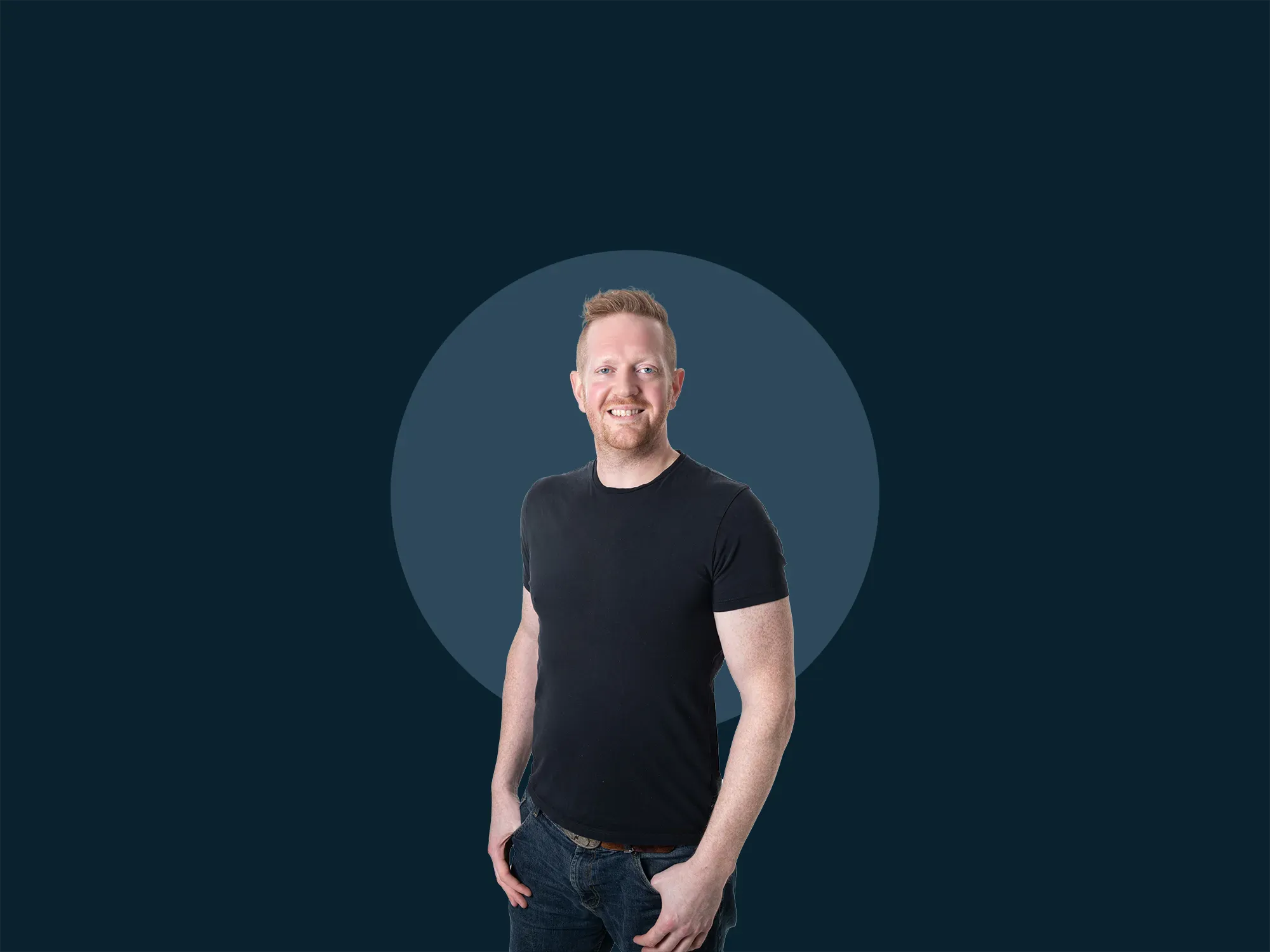 Man in a black t-shirt and jeans stands smiling against a dark blue background with a circular design.