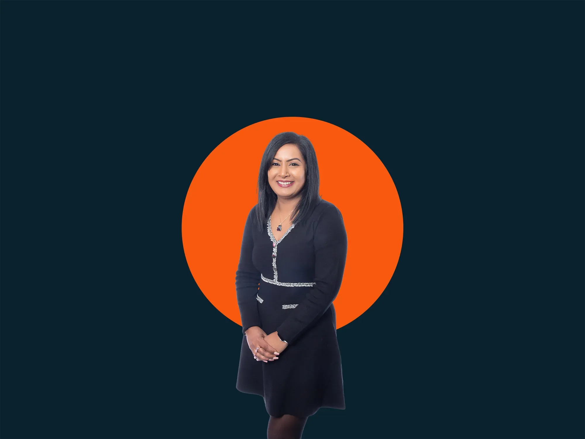 Woman in a black dress stands against a dark background with a bright orange circle behind her.