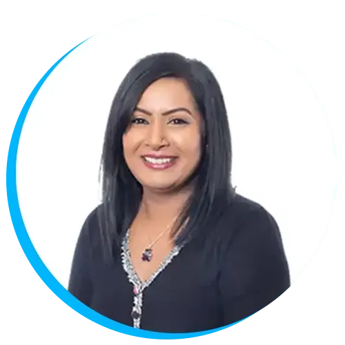 Arti Dhamu smiling with long black hair wearing a dark top and necklace, against a white background with a blue circular border.