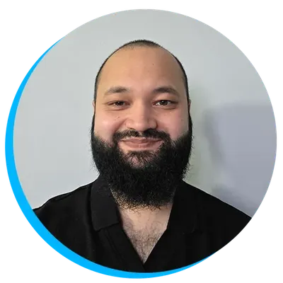 Headshot of Mo Amin smiling with a beard, wearing a black shirt against a light grey background with a blue circular border.