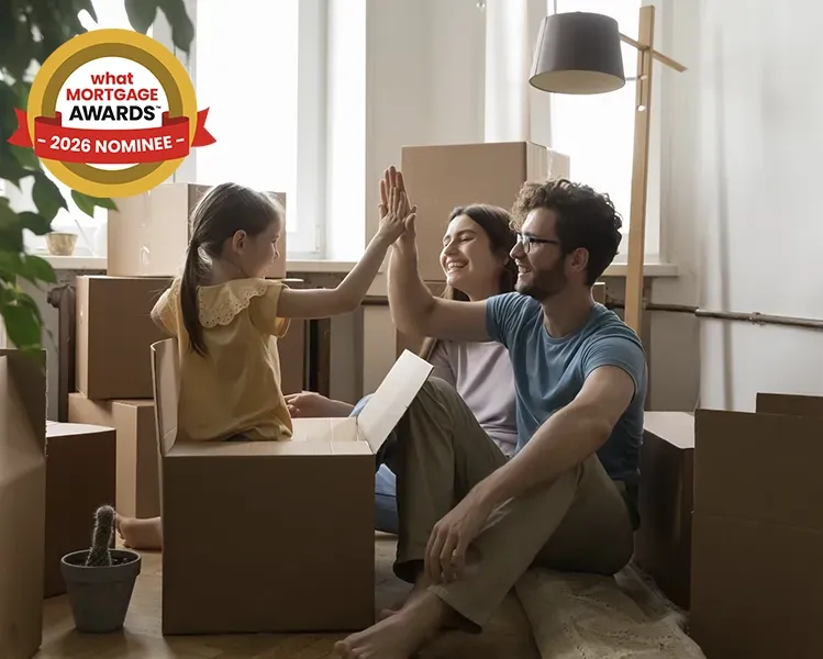 Family high-fiving in a room filled with cardboard boxes, indicating a recent move. A "What Mortgage Awards 2026 Nominee" badge is visible in the top left hand corner