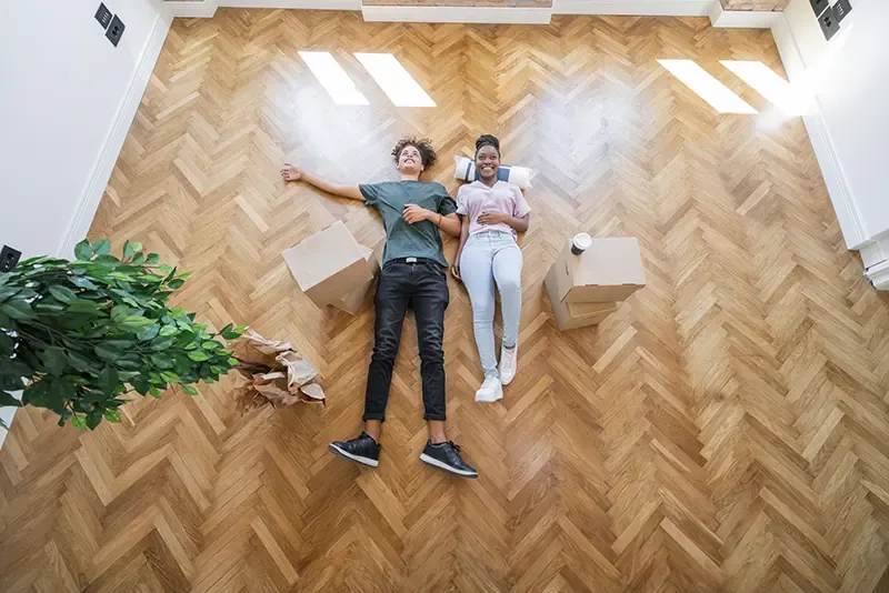 Young first-time buyers lying on the floor of their new home