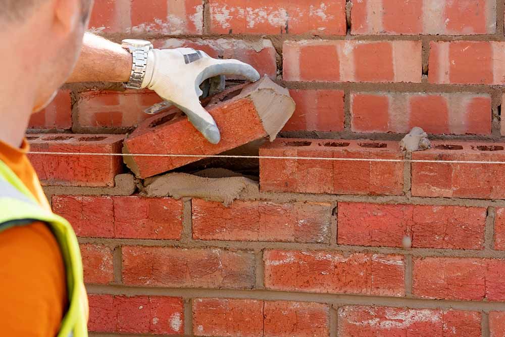 Bricklayer laying bricks on new house construction