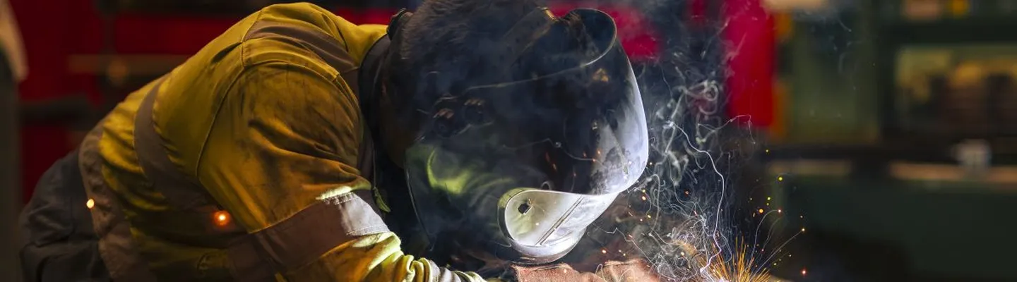 Sarens employee welding crane components while wearing protective equipment