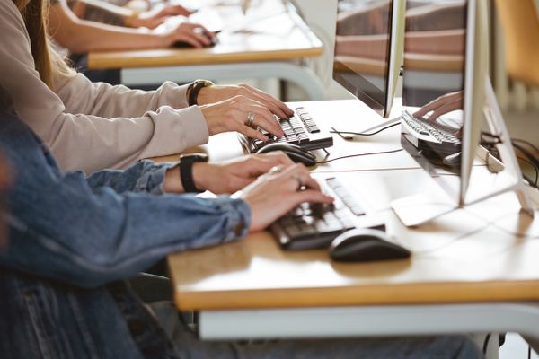 Schüler:innen tippen auf einer Tastatur.
