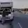 Ein Mann steht neben einem Wohnmobil mit geöffneter Motorhaube auf einer ländlichen Straße und telefoniert. Im Hintergrund sind Olivenbäume und die Abendsonne zu sehen.