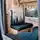 Innenraum eines Campervans mit waldinspirierten Sitzbezügen, Holzakzenten, einer grünen Pflanze und einem Fenster mit stilvollem Vorhang.