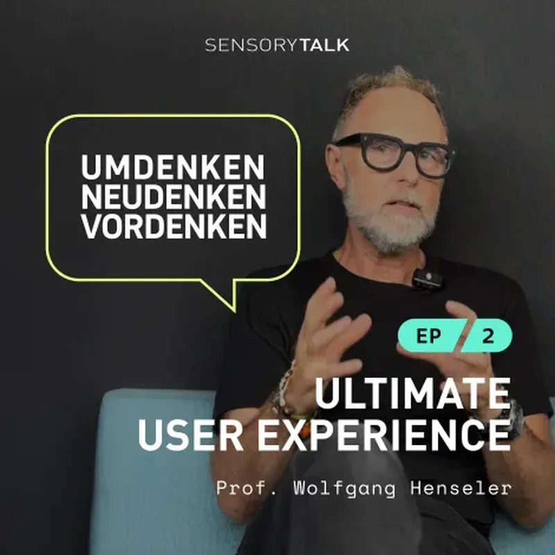 A bearded man with glasses, wearing a black shirt, gestures with his hands while speaking. The setting is minimal with a dark background and a light blue chair. Text reads: “SENSORYTALK”, “UMDENKEN, NEUDENKEN, VORDENKEN” (translated: Rethink, Rethink Anew, Think Ahead), “EP 2”, “ULTIMATE USER EXPERIENCE”, and “Prof. Wolfgang Henseler”.