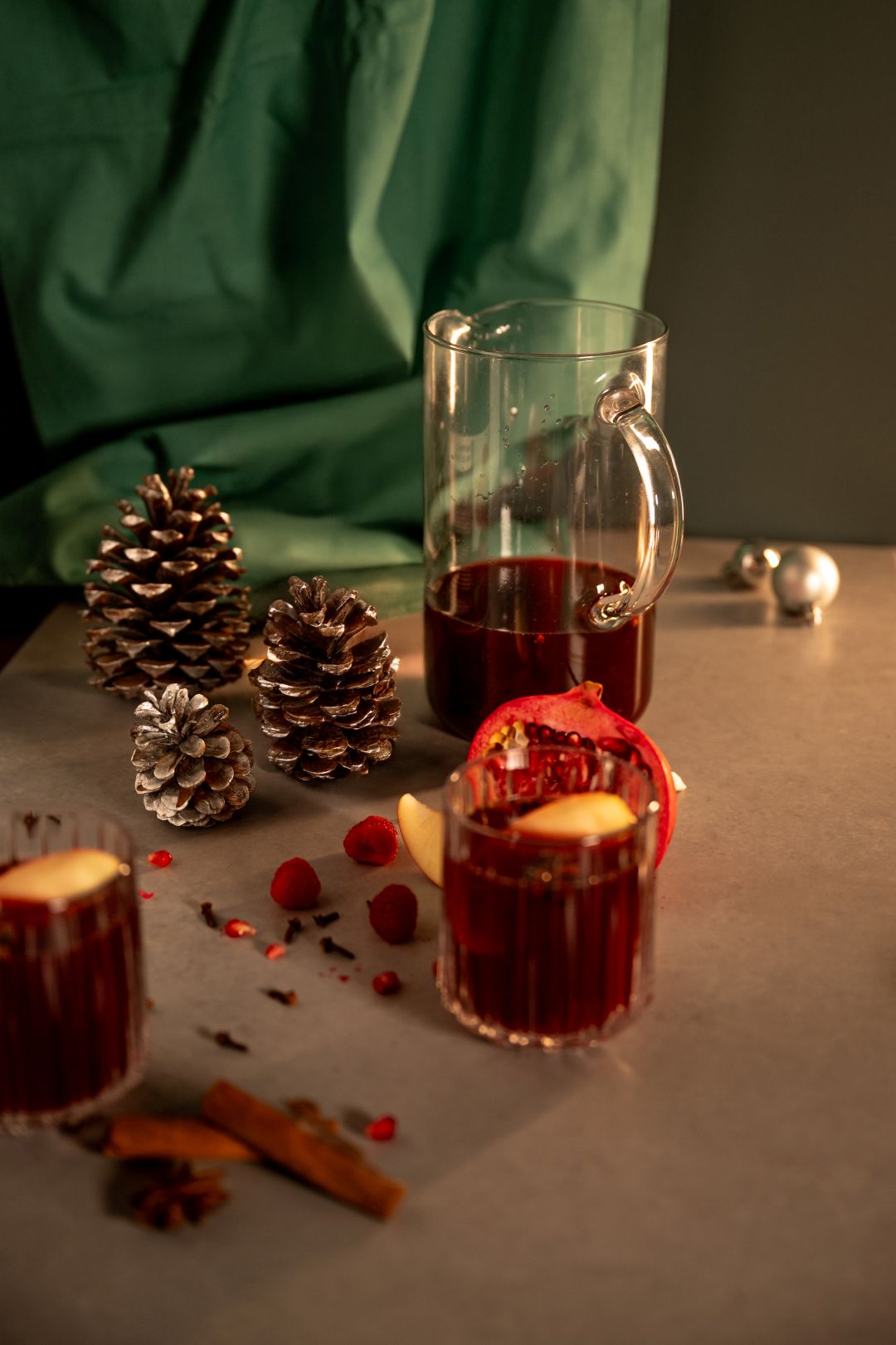 Winter Sangria in Karaffe mit Cranberrysaft und Orangensaft von granini mit Weihnachtsdeko auf Tisch, dunkel beleuchtet