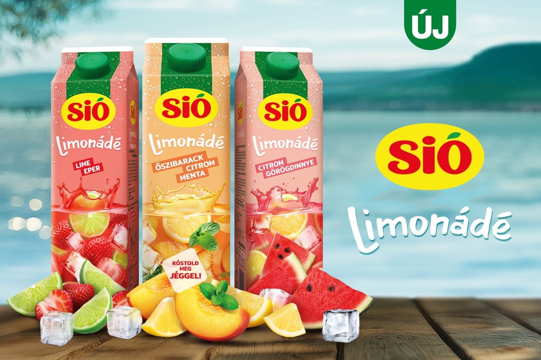 Sió Limonádé cartons in lime, peach mint, and lemon grapefruit flavors, with fresh fruits and ice cubes on a wooden surface by a lake.