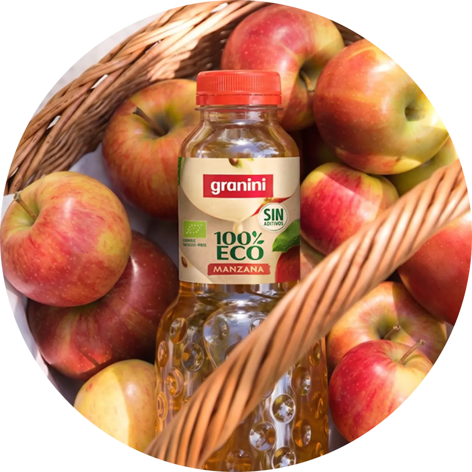 Una botella de zumo granini 100% Eco Manzana dentro de una canasta llena de manzanas rojas