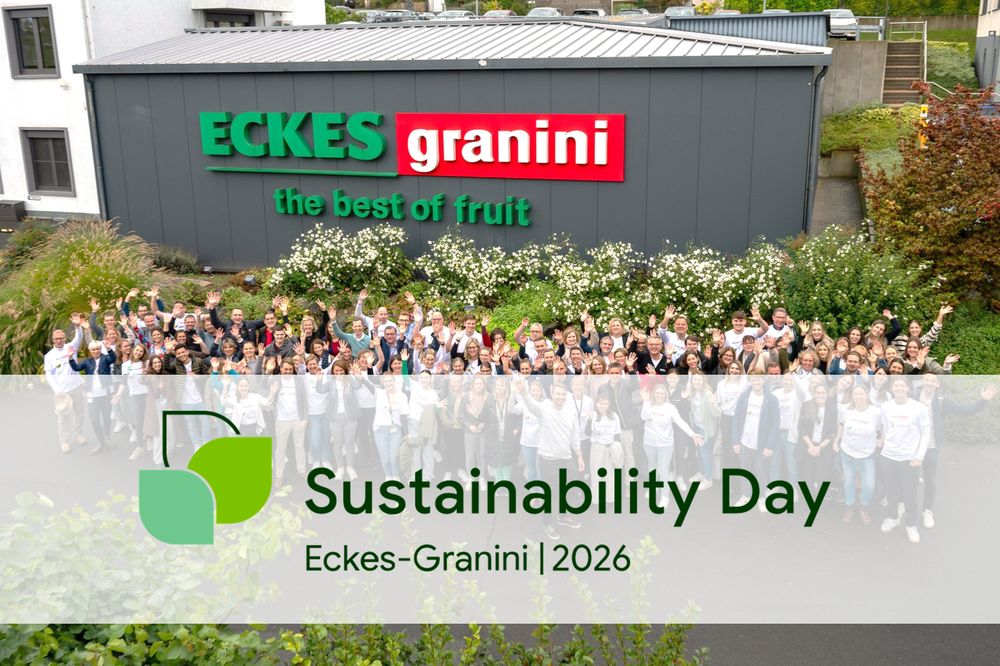 Group of people waving in front of Eckes-Granini building with "Sustainability Day" text overlay. Numerous plants and flowers in the foreground.