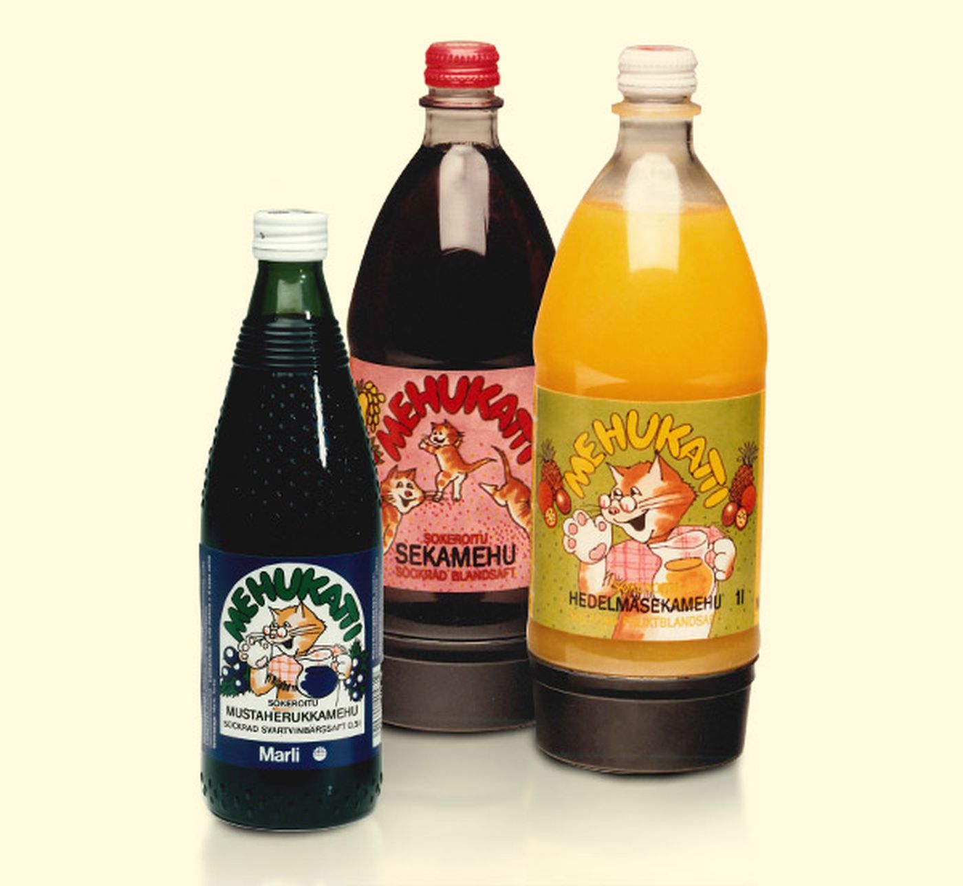 Three bottles of Mehukatti juice featuring colorful labels with a cartoon cat. Flavors include blackcurrant, mixed berry, and fruit blend.