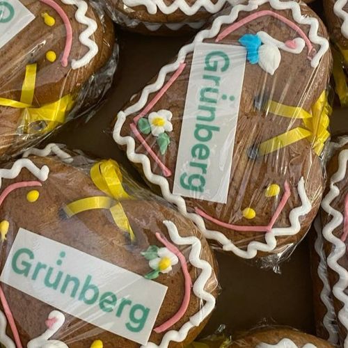 Several decorated gingerbread hearts in bright colors lie on a table, lovingly designed with lettering and sugar decorations.